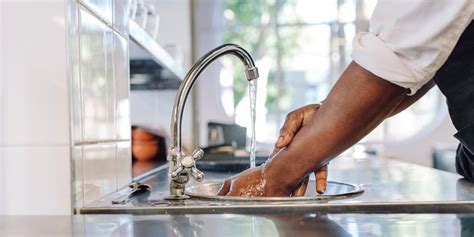 What should the temperature of the water be when washing hands Dried hands on a side towel. . A food worker washes her hands in the bathroom and is now returning to her work duties